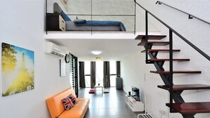 Ein modernes Wohnzimmer mit einer Couch, einer Treppe und einem Gemälde eines Turms.