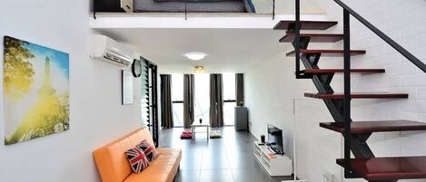 Una sala moderna con un sofá, una escalera y un cuadro de una torre.