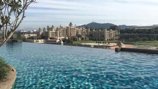 Una piscina con agua cristalina y una vista de un gran edificio de hotel al fondo.