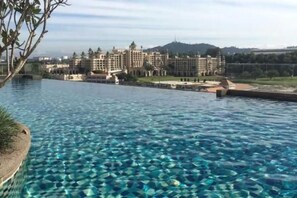 Une piscine à l’eau claire, avec en arrière-plan la vue d’un grand bâtiment d’hôtel.