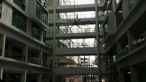 Un atrio de varios niveles con techo de cristal, arquitectura moderna y un espacio central abierto.