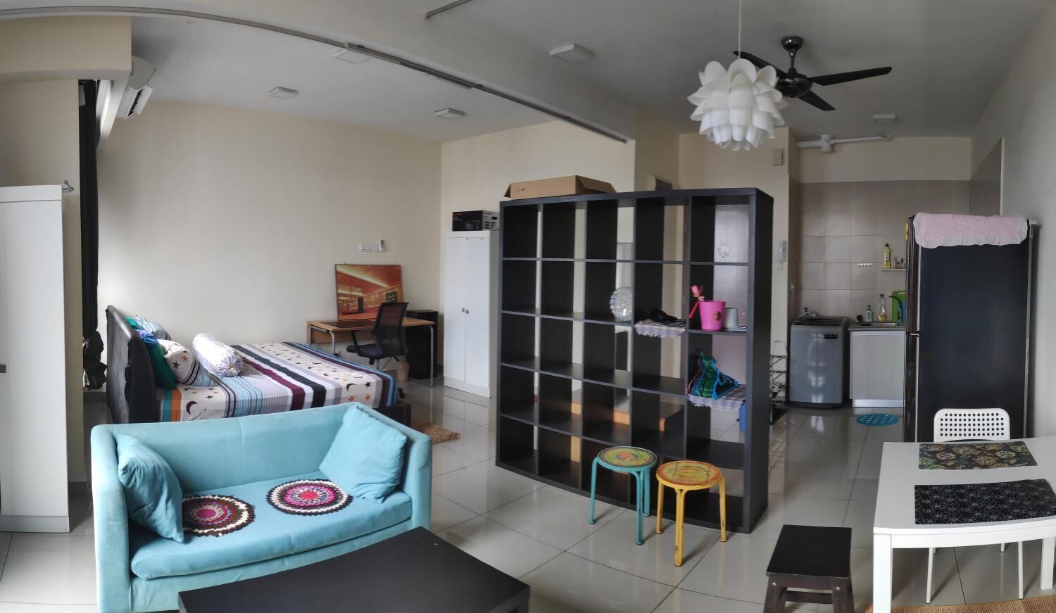 A compact living space with a sofa, a dining table, a kitchenette, and a ceiling fan.