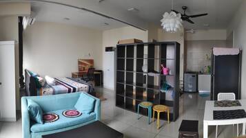 A compact living space with a sofa, a dining table, a kitchenette, and a ceiling fan.