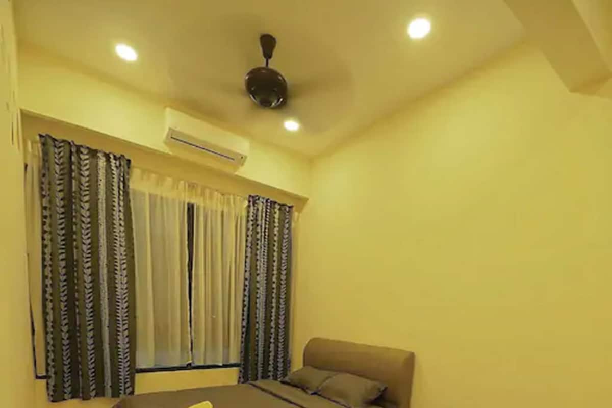 Ein Schlafzimmer mit zwei Betten, einem Deckenventilator und einer Klimaanlage.