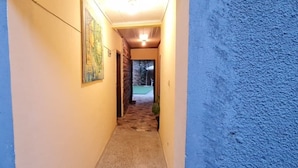A narrow hallway with a carpeted floor, a stone wall on one side, and a blue textured wall on the other. - Lucy Guest House B&B (Addis Ababa)