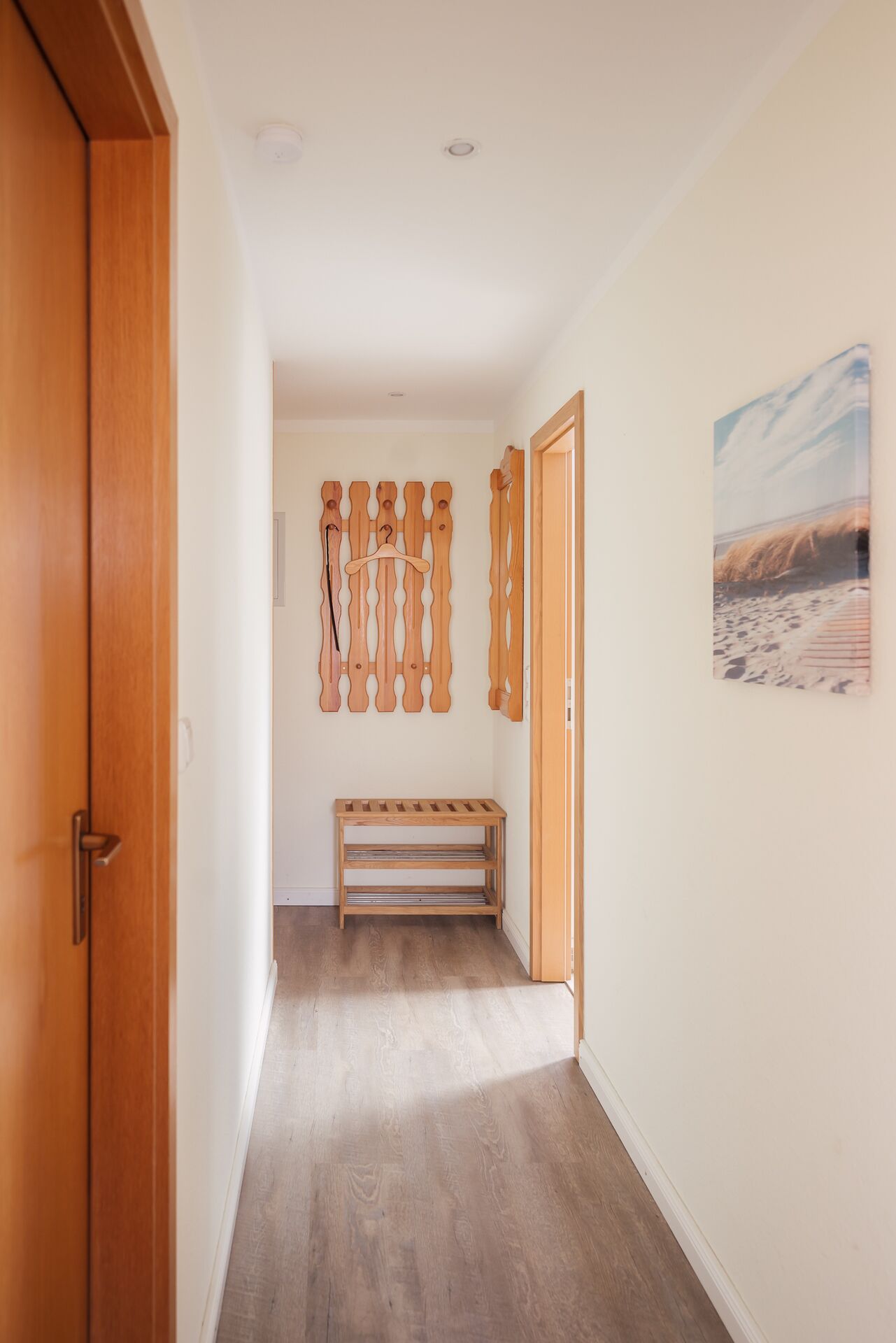 Ein Flur mit einer hölzernen Sitzbank, einem Holzanziehgestell und einem gerahmten Bild an der Wand.