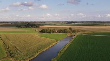 A rural landscape with a river, fields, and a distant wind farm.