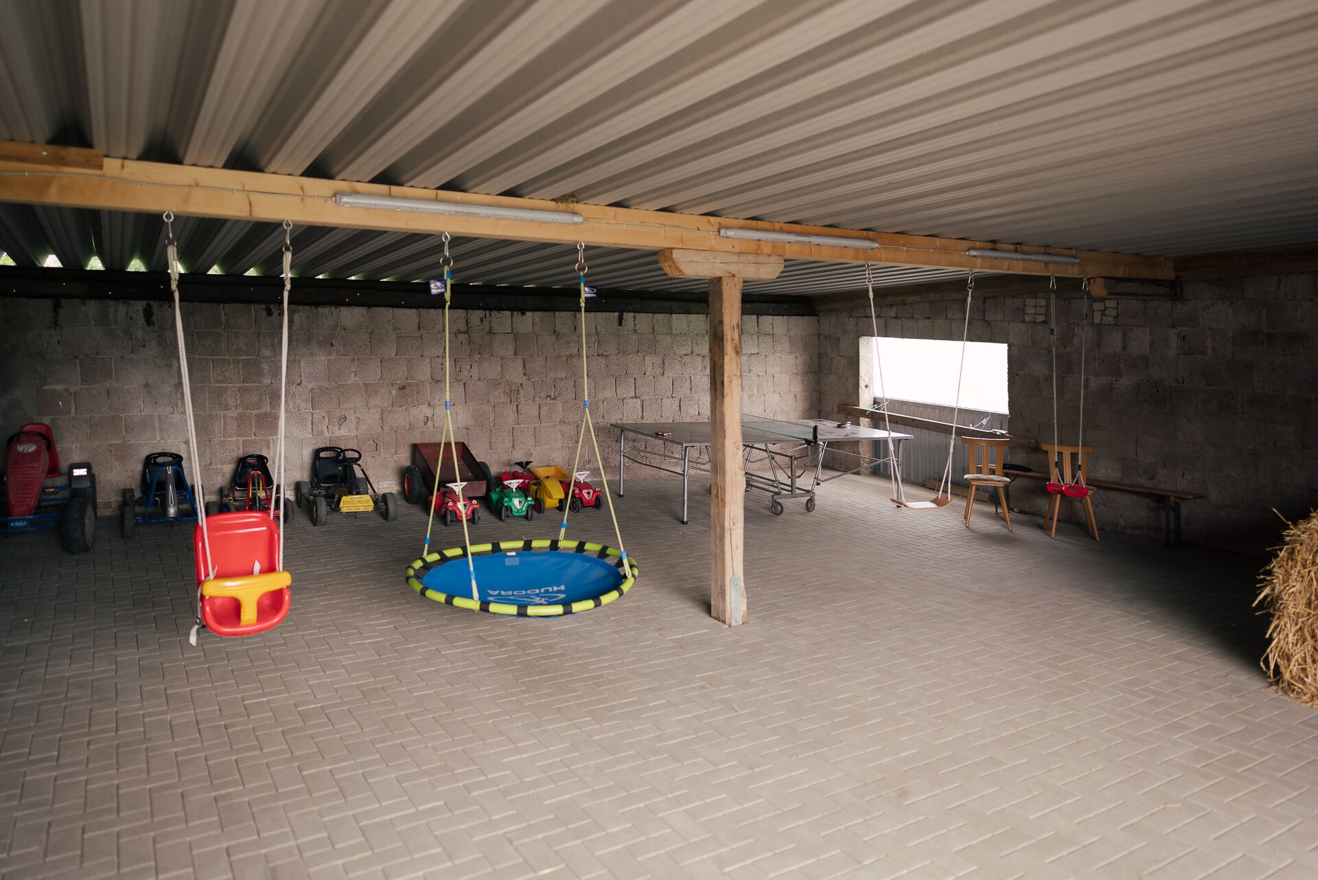 A spacious indoor area with a trampoline, various children's toys, and a ping pong table.