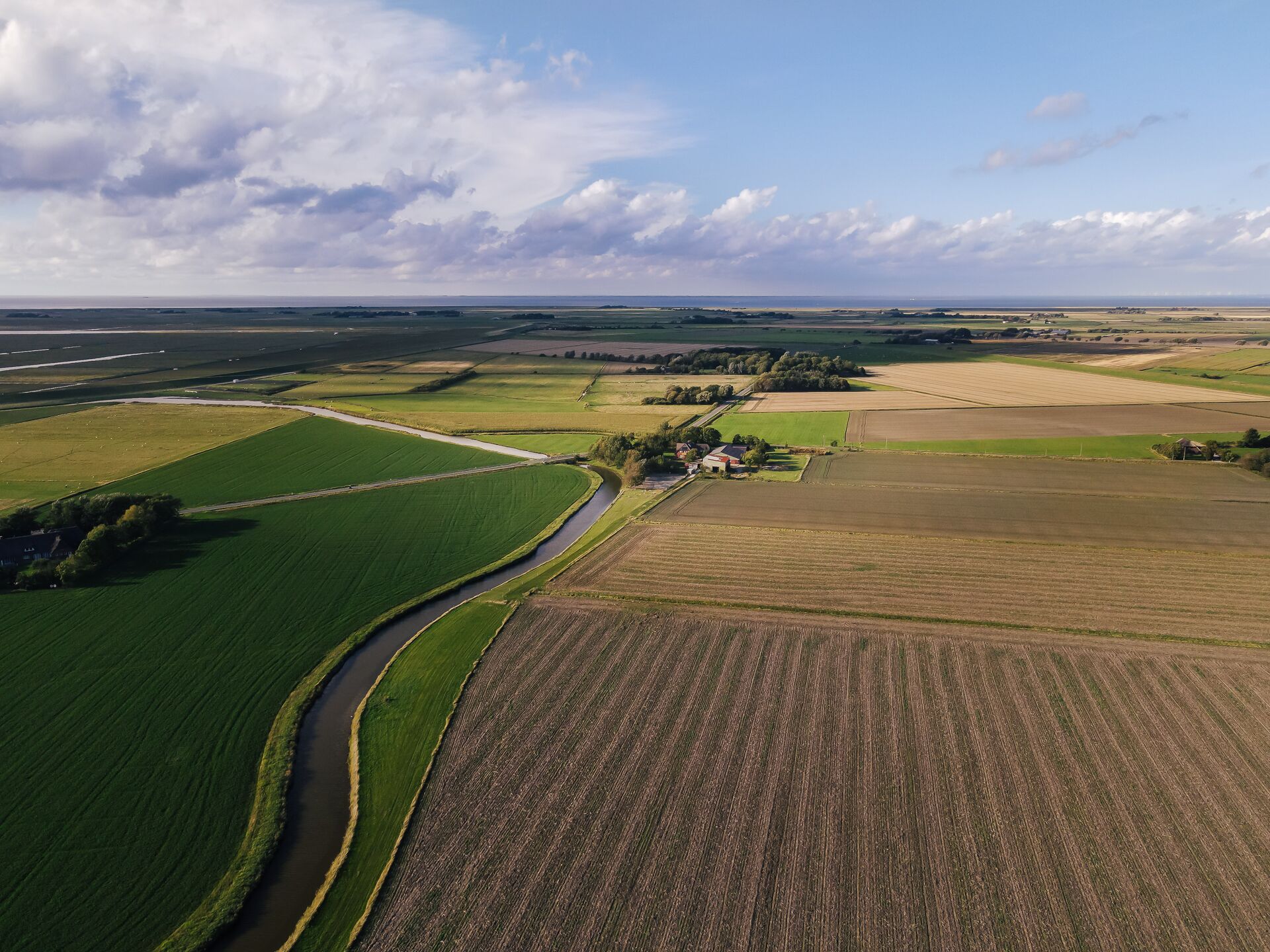 Vista aérea de un paisaje rural con campos, un río y un pequeño conjunto de edificios.