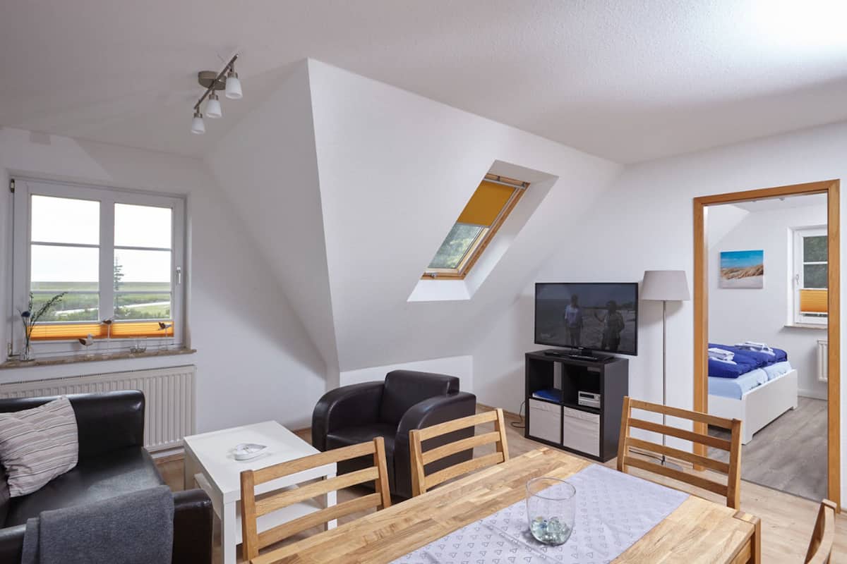 Ein kompakter Wohnraum mit Essbereich, einer Couch, einem Fernseher und einem Oberlicht.
