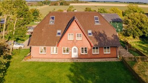 A red brick house with a gabled roof and a small front porch. - FEWO auf dem Lande (Tumlauer Koog)