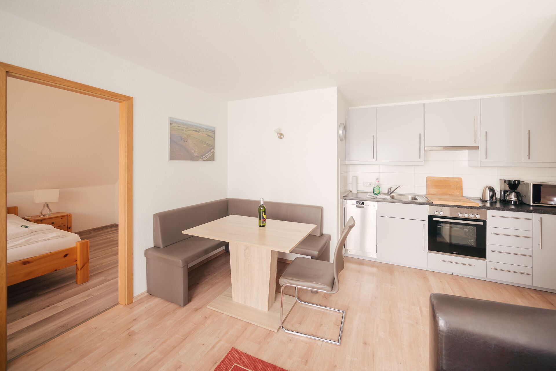 A compact living space with a kitchenette, a dining area, and a bedroom.