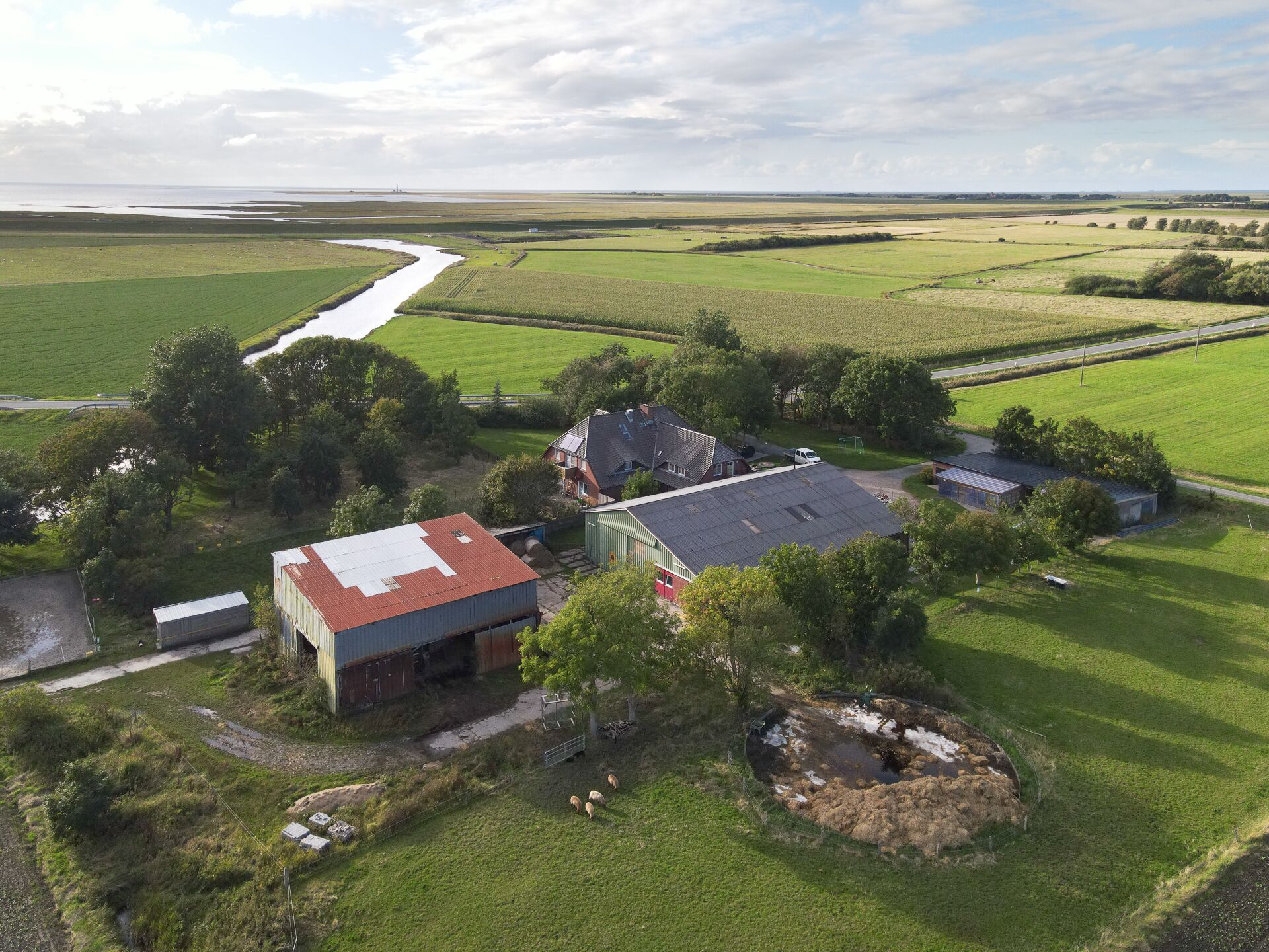 A rural farmstead with a large barn, a smaller building, and a pond.