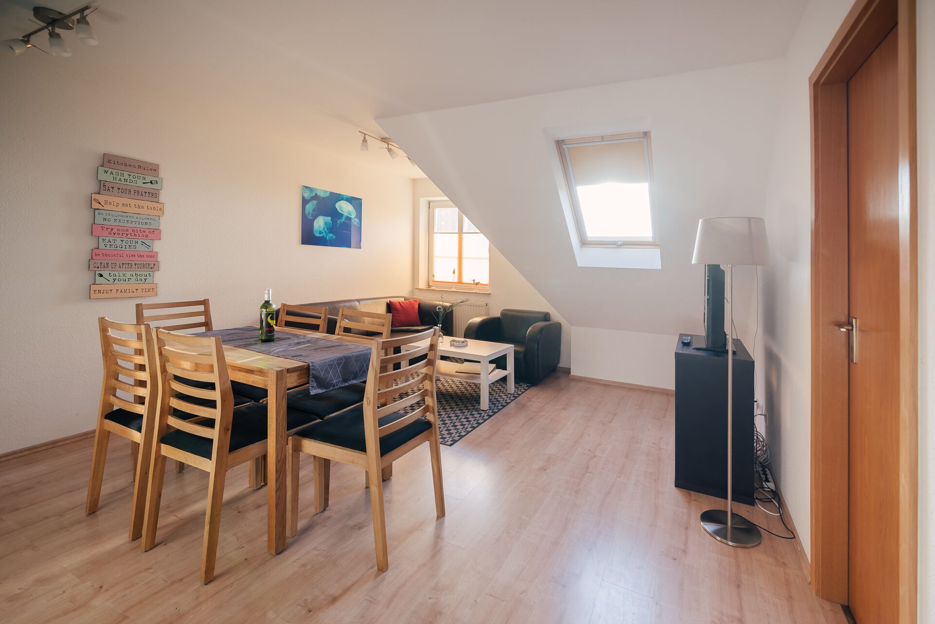 A cozy loft apartment with a dining area, a sofa, a TV, and a window.