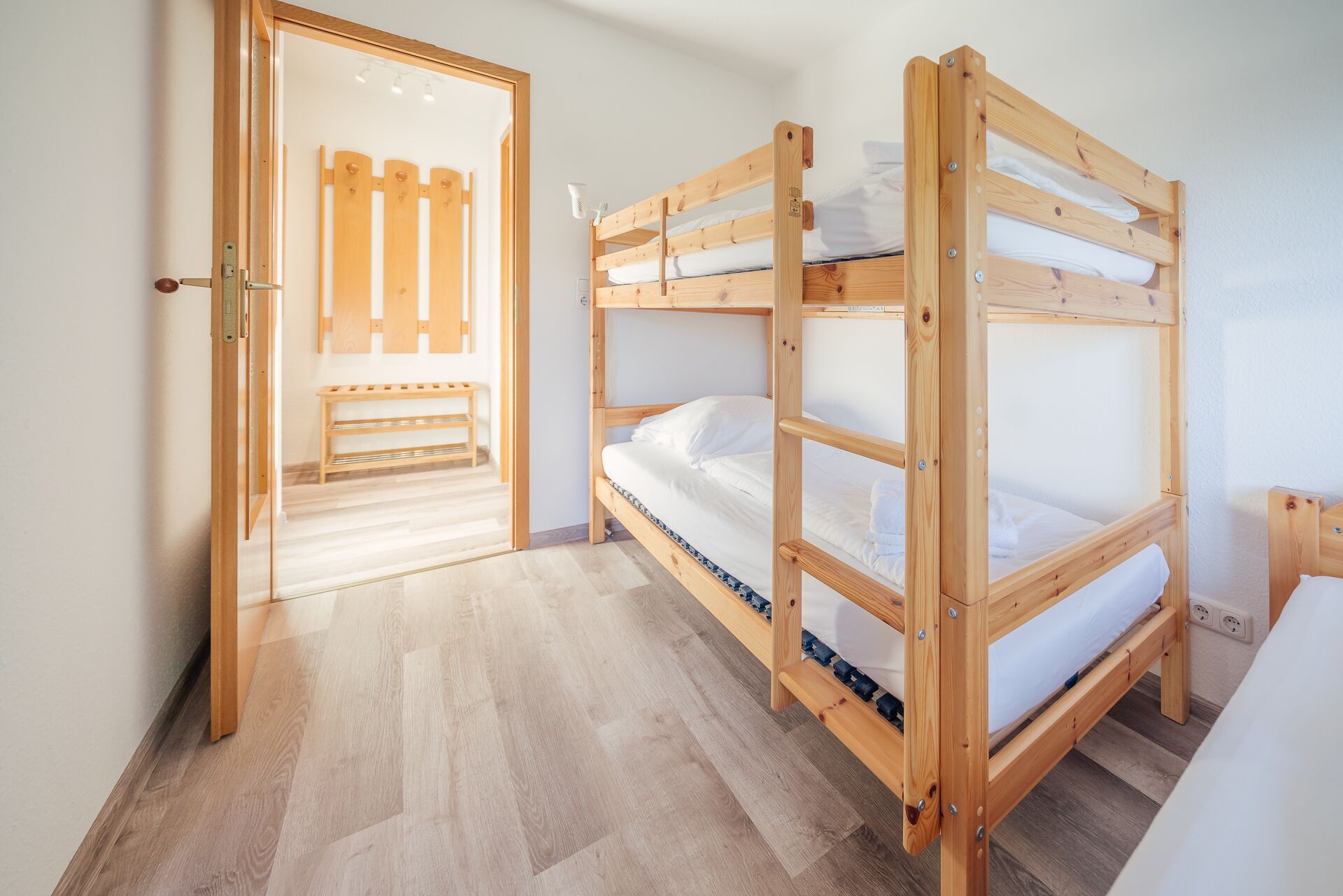 Una habitació amb dos llits búnquers, una panxa de rata i una porta que dona a una altra habitació.