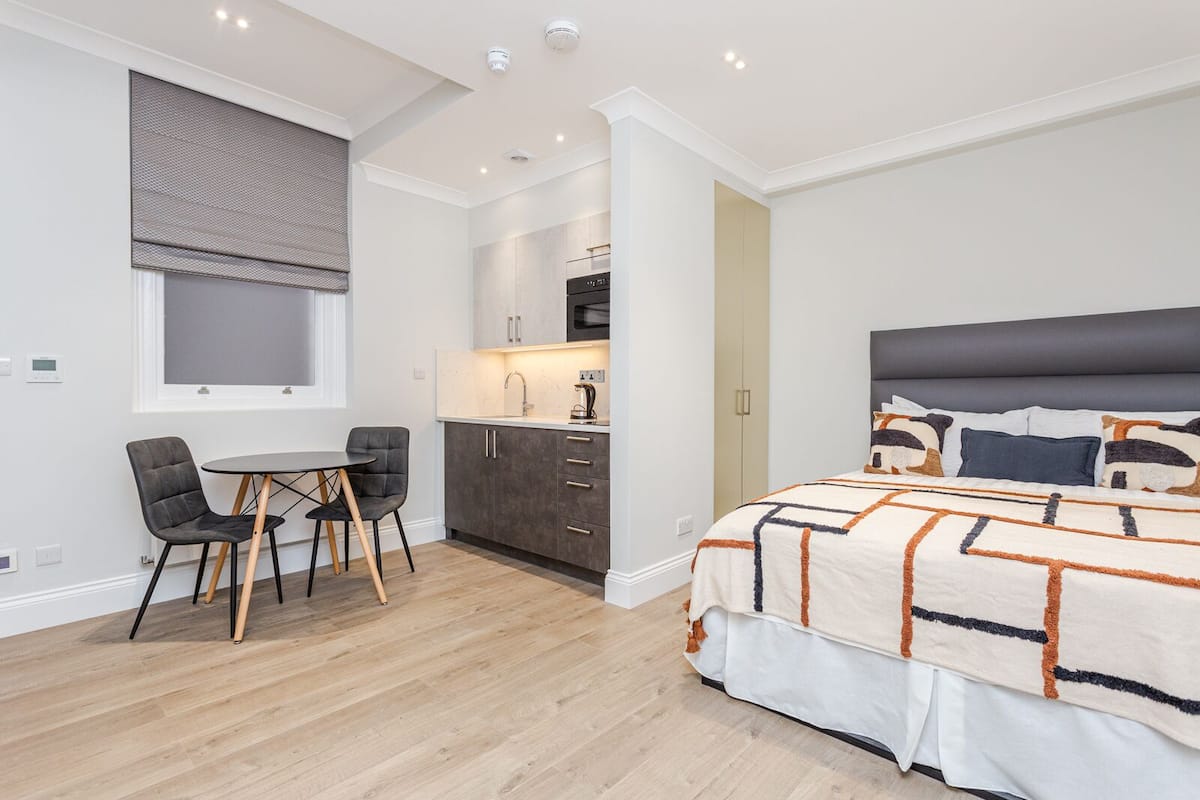 Une chambre moderne dotée d’un grand lit, d’une petite kitchenette et d’un coin repas avec une table et des chaises.
