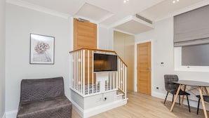 A modern living room with a staircase, a dining area, and a door leading to another room.