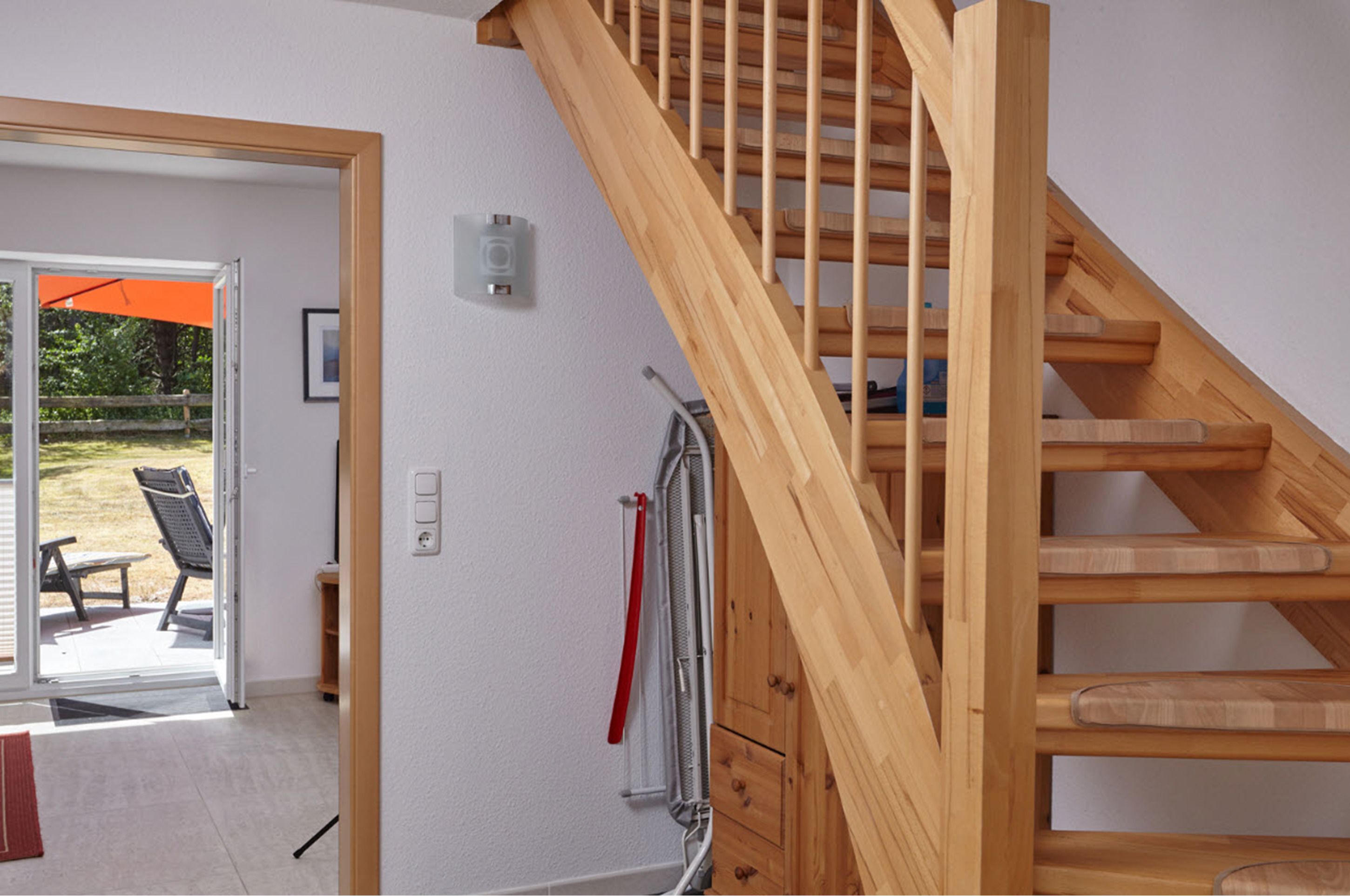 A wooden staircase leading to an upper floor, a sliding glass door to an outdoor area, and a red towel on a rack.