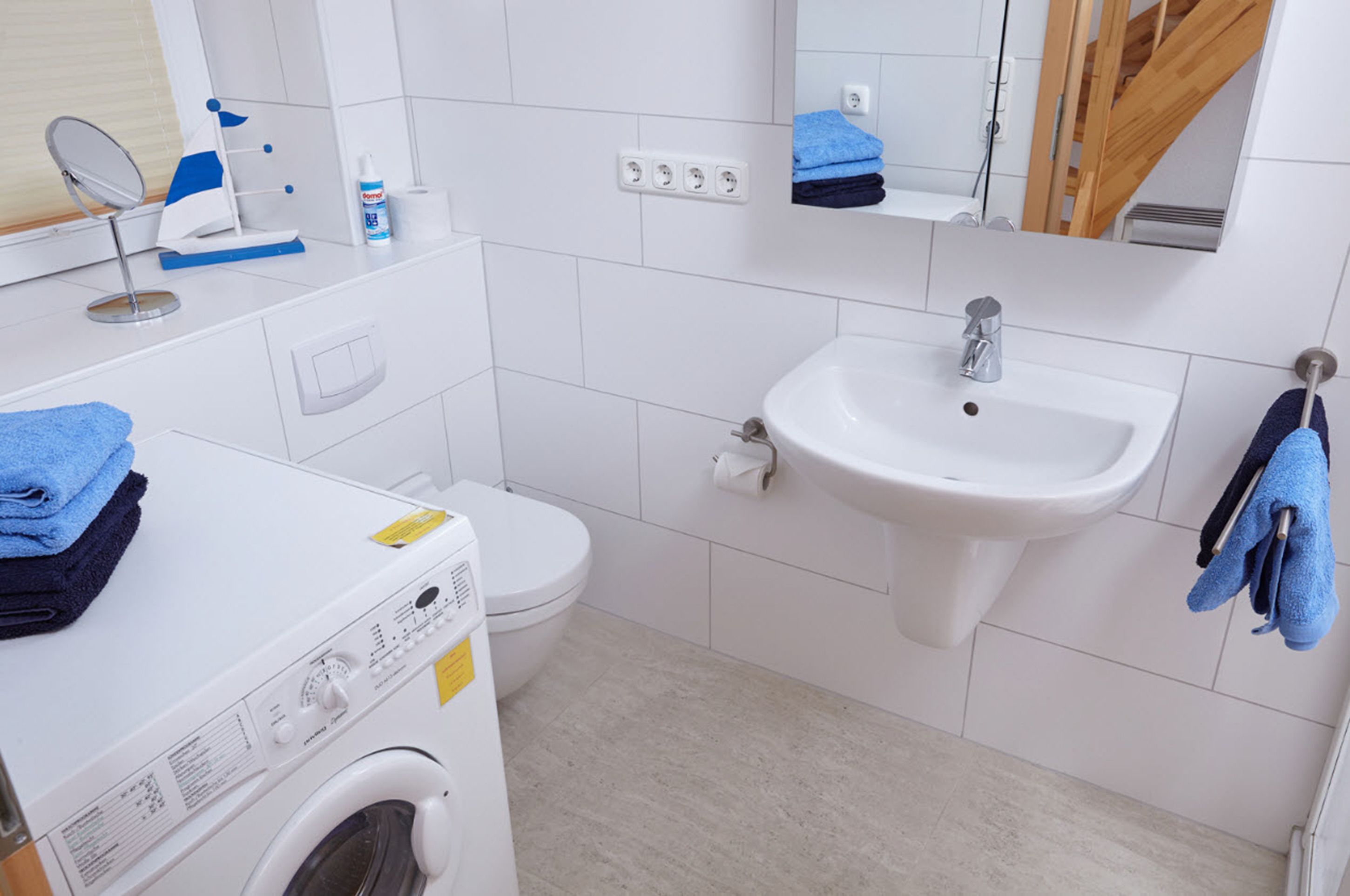 A compact bathroom with a washing machine, a sink, and a toilet.