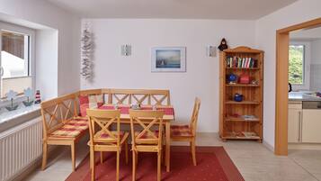 Enjoy meals with family and friends at the central dining table, surrounded by a bookshelf and a view of the outdoors.