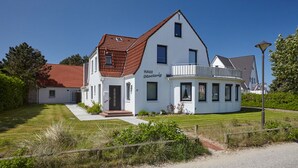 Una casa de dos pisos con fachada blanca y tejado de tejas rojas.