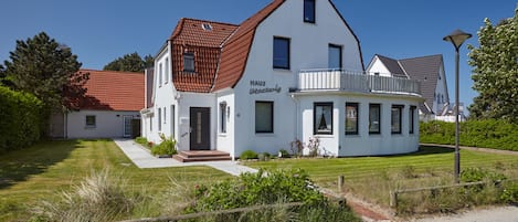 A two-story house with a white exterior and a red-tiled roof.
