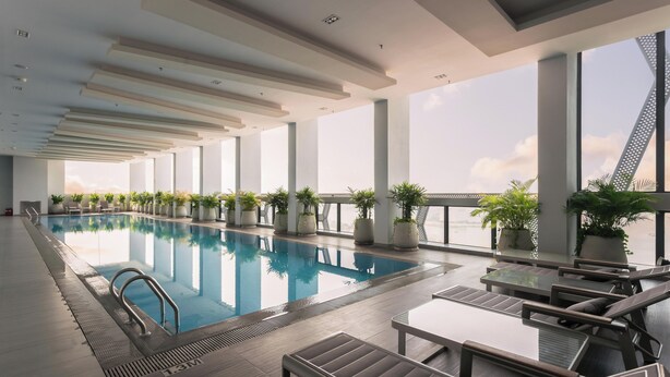 A rooftop infinity pool with lounge chairs and potted plants, large windows, and a modern architectural design. - The Snowbell Hotel & SPA @ The Bridge. (Phnom Penh)