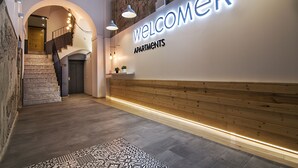 A reception area with a staircase, a reception desk, and a wall with a 'Welcome Apartments' sign. - Welcomer Apartments Valencia (Valencia)