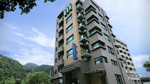 A multi-story building with a modern architectural design, featuring balconies and a prominent entrance. - Ruo Shui Hotspring Hotel (Jiaoxi)