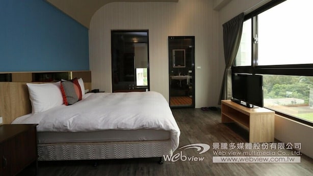 A modern hotel room with a large bed, a television, and a view of the outdoors. - Ruo Shui Hotspring Hotel (Jiaoxi)