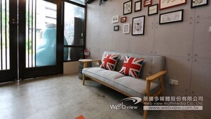 A modern interior with a sofa, framed artwork on the wall, and a large window. - Ruo Shui Hotspring Hotel (Jiaoxi)