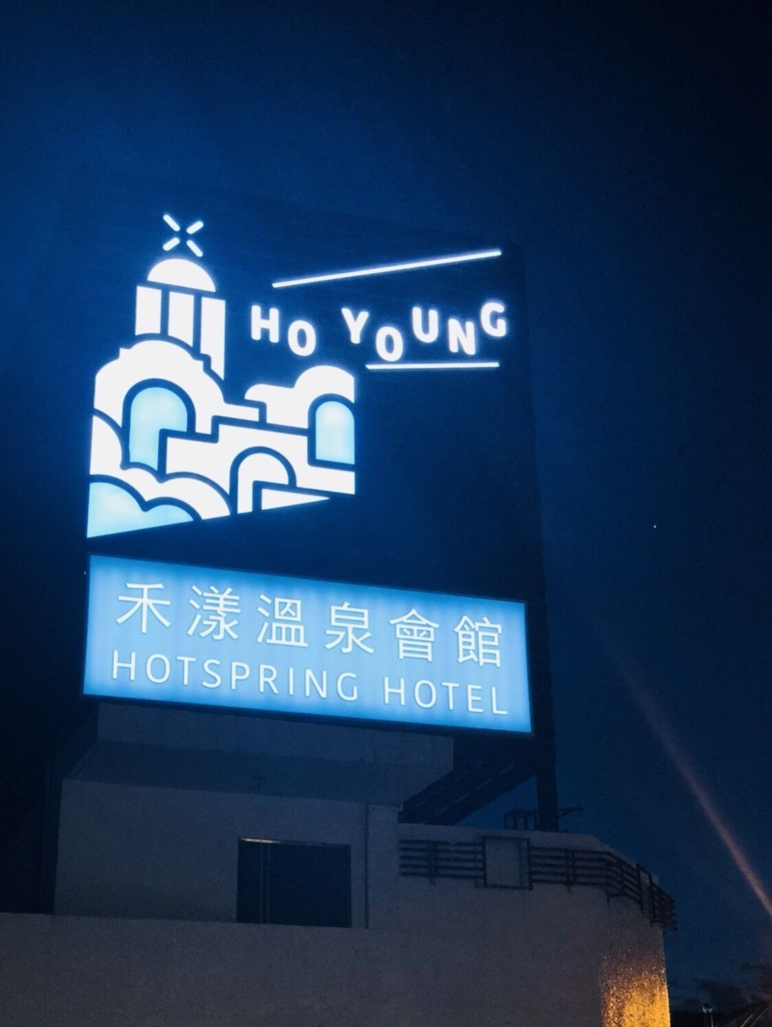 Letrero nocturno del Hotel Ho Young Hot Spring, con un edificio estilizado y el nombre del hotel.