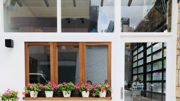 A building with a white brick facade, a wooden window frame, and a stone-paved entrance. - Ho Young Hotspring Hotel (Jiaoxi)
