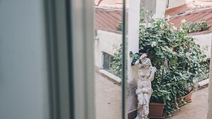 A statue of a woman in a courtyard with potted plants and a tiled floor. - Spagna Rooms (Rome)