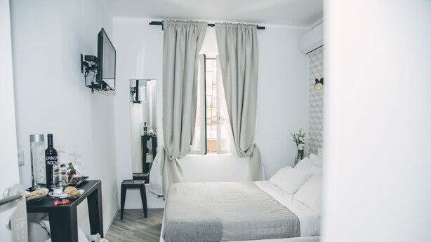 A modern bedroom with a bed, a desk with a mirror, and a window with curtains. - Spagna Rooms (Rome)