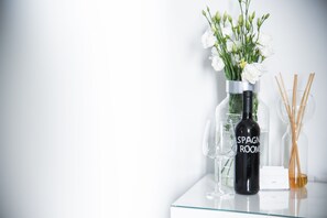 A glass table with a bottle labeled "SPAGNE ROOM" and a vase with white flowers. - Spagna Rooms (Rome)