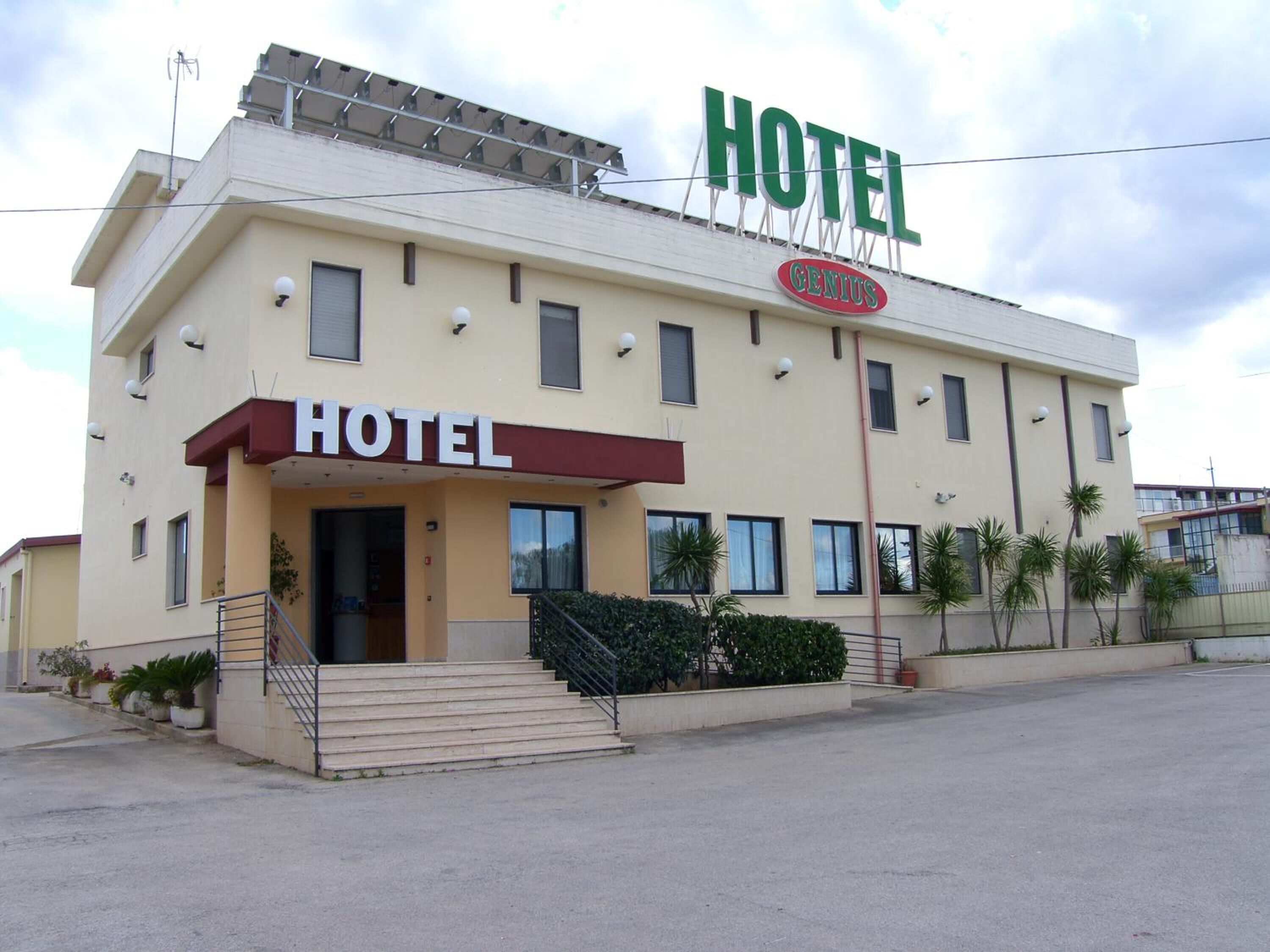 A two-story hotel with a sign reading "HOTEL" and "GENIUS" on the facade.