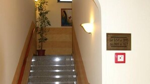 A staircase with a handrail, a potted plant, and a wall-mounted sign with numbers. - Genius Hotel (Corato)