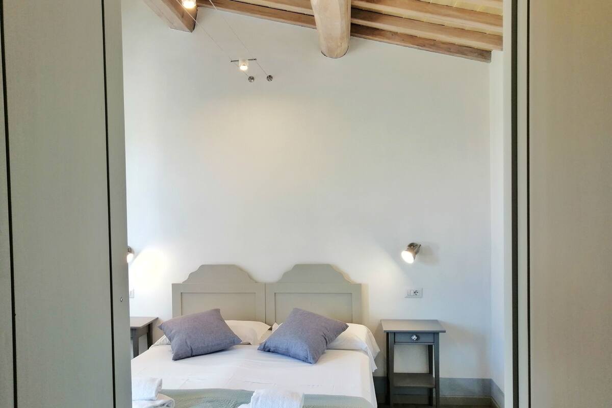 Une chambre à coucher avec un lit, des oreillers, une table de chevet et une commode.