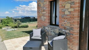 Een terras met rieten meubels en een stenen muur.