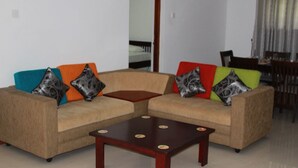 A living room with a beige sectional sofa, a small wooden coffee table, and colorful pillows.
