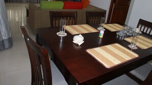 A dining area with a wooden table set for four, including placemats, glasses, and a napkin.