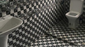 A bathroom with a checkered floor, a sink, a toilet, and a shower.