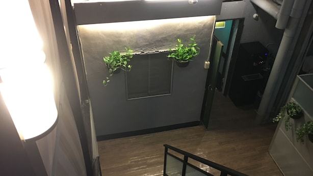 A staircase with a metal railing, a wooden floor, and two potted plants on the wall. - HUA CHUN LIN Hotel (New Taipei City)