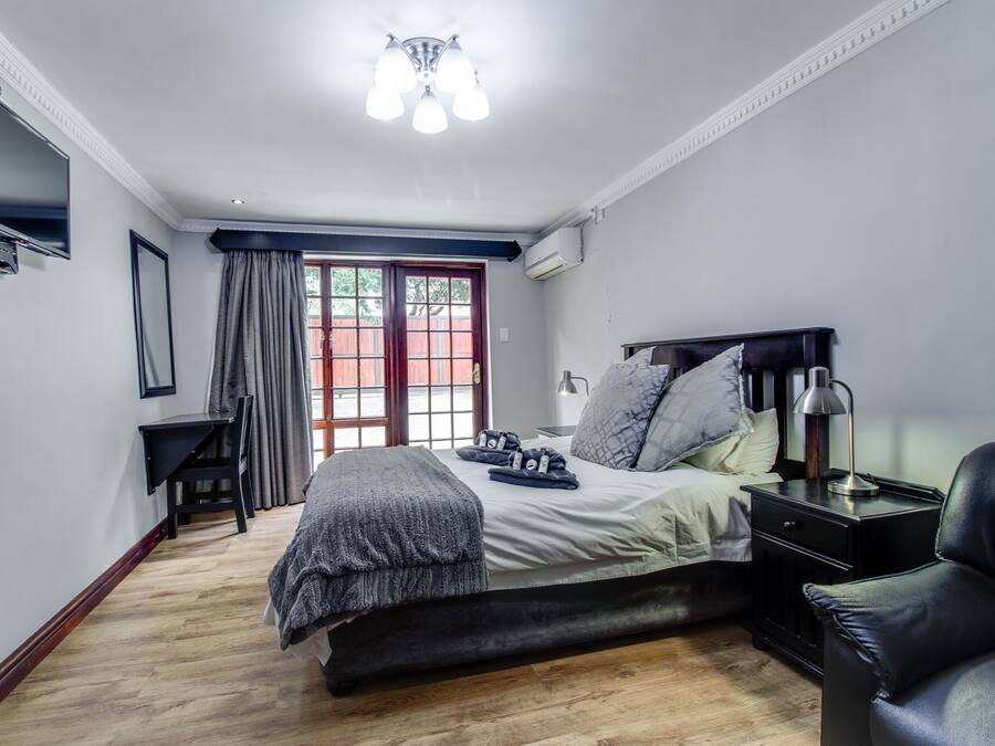 Ein Schlafzimmer mit Bett, Nachttisch, Lampe und einem an der Wand montierten Fernseher.