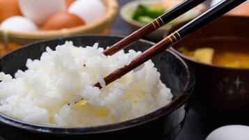 A bowl of white rice with chopsticks resting on top.