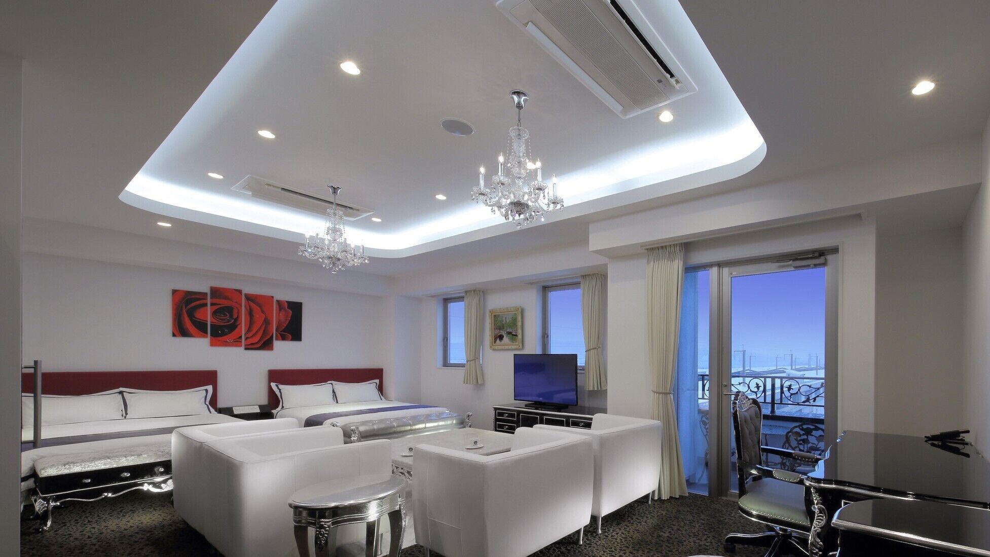 Une chambre d’hôtel comprenant un lit, deux canapés, une télévision, un balcon avec vue et un lustre.