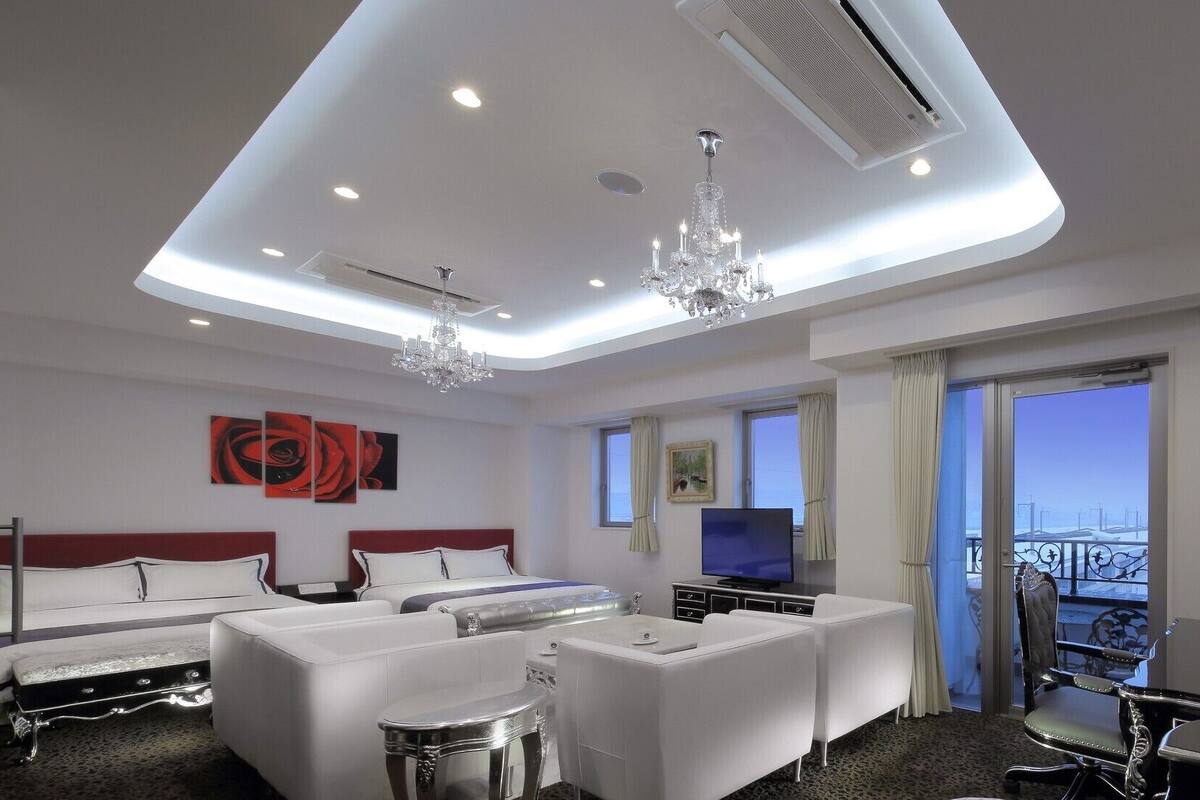 Une chambre d’hôtel comprenant un lit, deux canapés, une télévision, un balcon avec vue et un lustre.