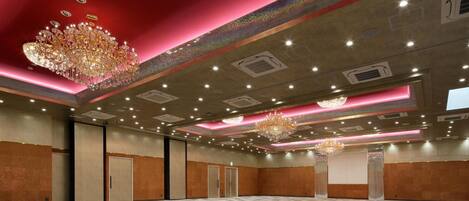 Un salón amplio con suelo estampado, múltiples candelabros y techo rojo.