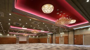Une salle de conférence spacieuse, dotée d’un tapis à motifs, d’un éclairage encastré et d’un grand lustre.